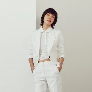 A woman wearing a white top and white suit