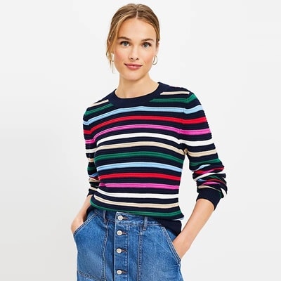 A woman wearing a striped sweater and a jean skirt