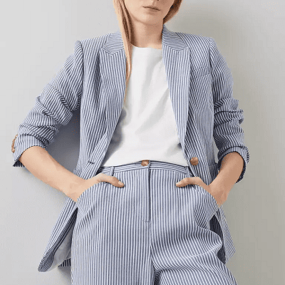 blue and white striped suit; model is slouching against wall with her hands in pants pockets