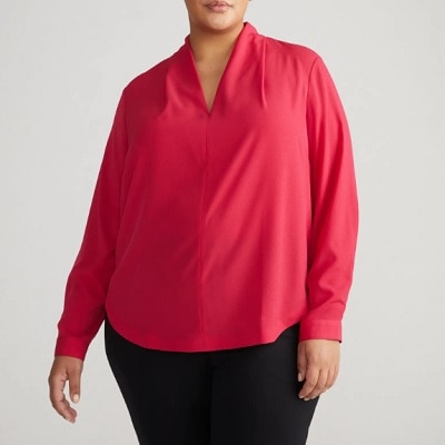 A woman wearing a pink long sleeve v neck top and black pants