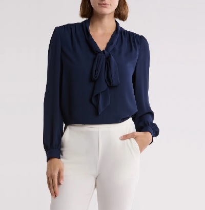 A woman wearing a blue long sleeve sheer top and white leggings