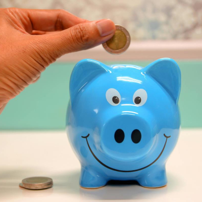 person adds coin to blue piggy bank