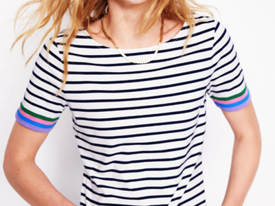 woman wears cute striped top for work, a black and white Breton tee with pink and purple details at the sleeves