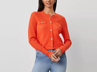 A woman wearing an orange cardigan and jeans