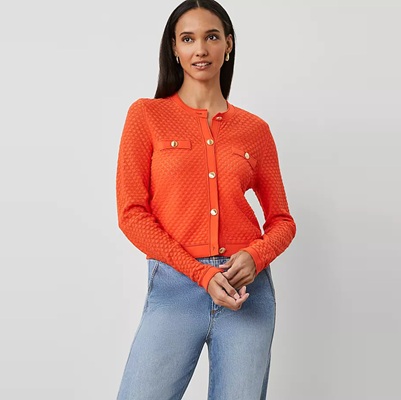 A woman wearing an orange cardigan and jeans