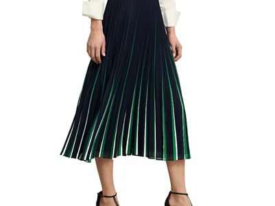 A woman wearing an off-white blouse, black strappy heels, and a black, white, and green midi skirtt