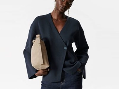 A woman wearing dark blue jeans, a navy blazer, and carrying a tan handbag