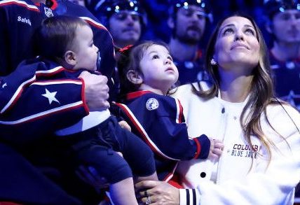COLUMBUS, OHIO - OCTOBER 15:  Sean Monahan #23 of the Columbus Blue Jackets stands on the ice while holding former Columbus Blue Jackets player Johnny Gaudreaus son, Johnny Jr, along side Gaudreaus wife and daughter, Meredith and Noah, and his brother-in-law Eddie Morris, during a remembrance ceremony prior to the start of the game against the Florida Panthers at Nationwide Arena on October 15, 2024 in Columbus, Ohio. Gaudreau and his brother Matthew were killed when hit by a suspected drunk driver on August 29, 2024.(Photo by Kirk Irwin/NHLI via Getty Images)