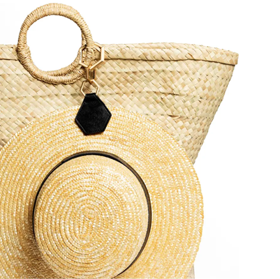 wide-brimmed hat is clipped to a handbag via a keychain-style charm