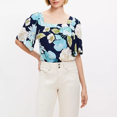 A woman wearing a floral printed square top and white pants
