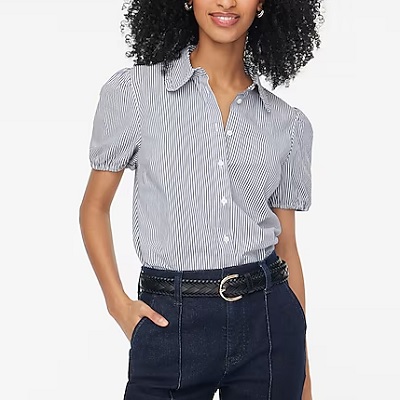 A woman wearing a blue pinstripe button-front shirt and dark blue jeans with black belt