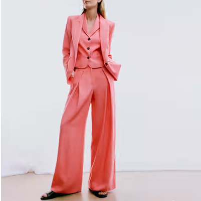 woman wears matching pink blazer, vest, and wide pleated pants with flat black sandals