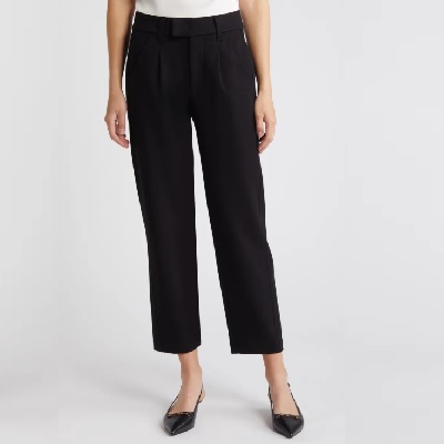 A woman wearing a white top and black trouser pants with black pointed flats