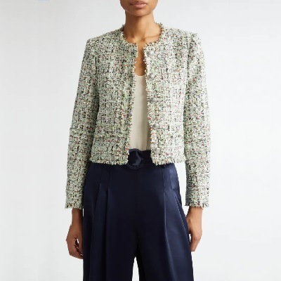 A woman wearing a metallic tweed jacket with white top and dark blue trouser pants