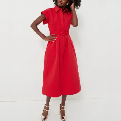A woman wearing a red short sleeve collared long dress with silver heels