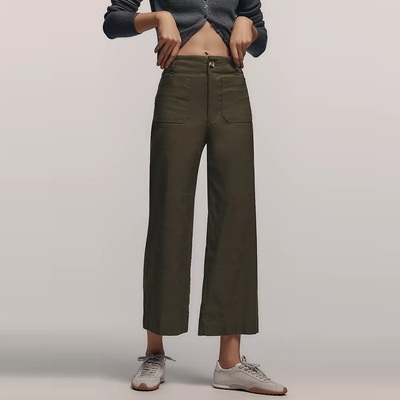 A woman wearing light gray sneakers, dark olive pants, and a gray cardigan