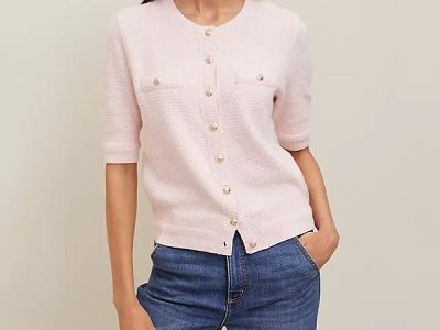 A woman wearing a light pink cardigan top and denim pants