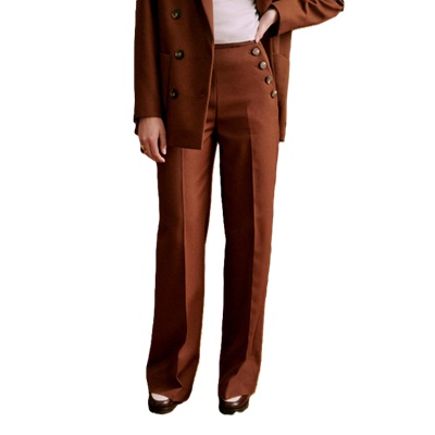 A woman wearing a rust-brown suit with white top and Oxfords