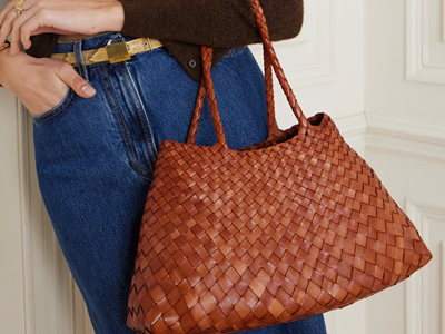 woman holds brown woven leather tote
