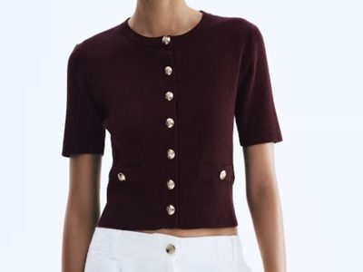 A woman wearing a maroon short sleeve top and white pants