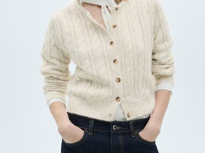 A woman wearing a white top under an ivory cardigan with dark blue denim pants