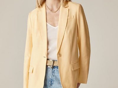 A woman wearing a white inner top with yellow blazer top and light denim pants