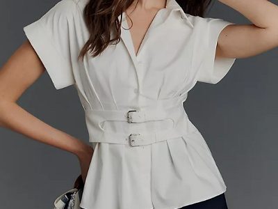 A woman wearing a white top with collar and double buckle