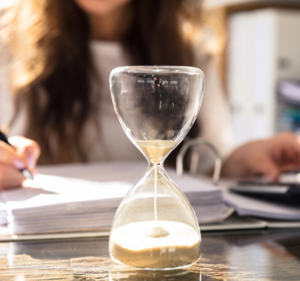 businesswoman works while an hourglass runs out of time