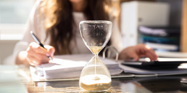 businesswoman works while an hourglass runs out of time