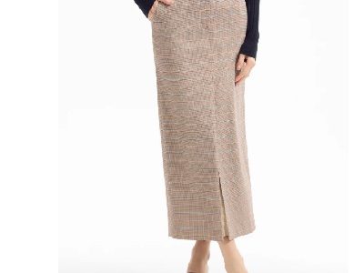 A woman wearing a brown plaid midi skirt with brown sandals and a black top