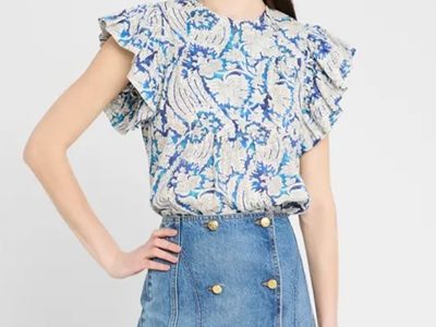 A woman wearing a blue and white printed top and denim skirt