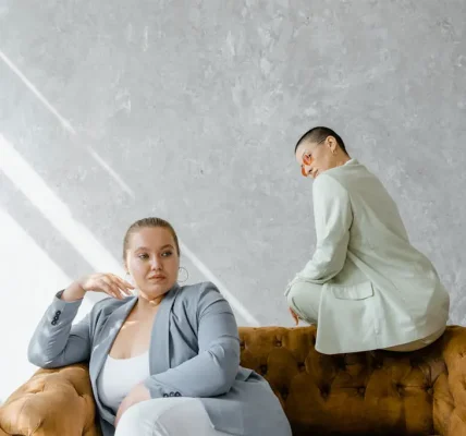 Two stylish women in suits, sitting on a couch, exemplifying body positivity.