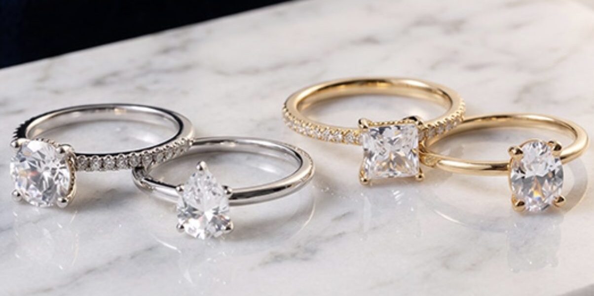 Four engagement rings from Rare Carat displayed on a textured surface, showing off their brilliance and fire