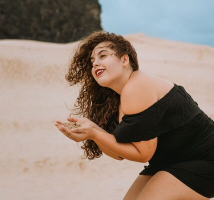 Woman in a black dress at the beach enjoying sand. Perfect for summer and leisure themes.