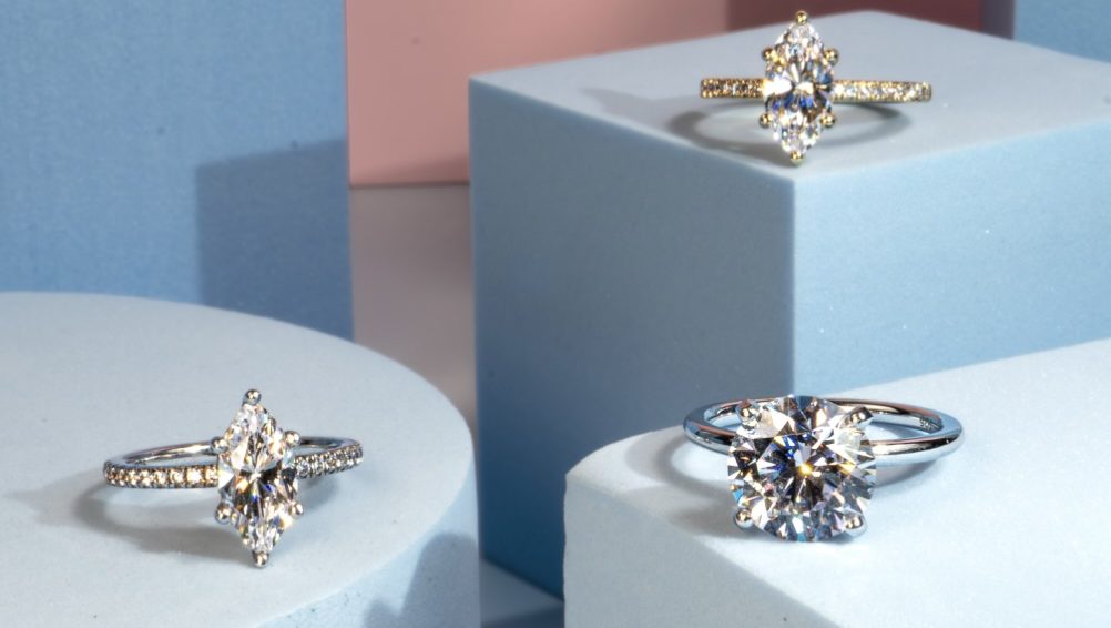 solitaire engagement rings in cushion, oval, and pear cut displayed on elevated blue boxes