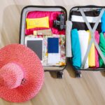 top view of a suitcase packed with clothes a camera and a sun hat ready for summer travel. 8212231 scaled e1783078111254