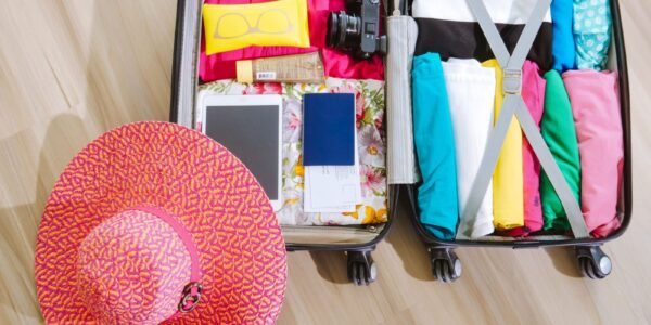 top view of a suitcase packed with clothes a camera and a sun hat ready for summer travel. 8212231 scaled e1783078111254