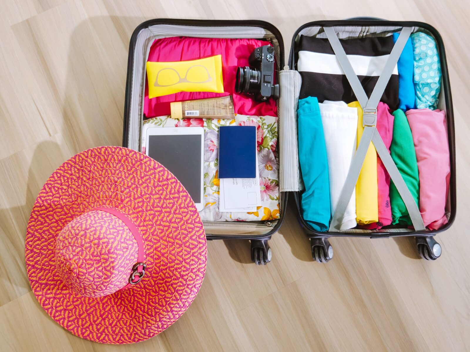 top view of a suitcase packed with clothes a camera and a sun hat ready for summer travel. 8212231 scaled e1783078111254