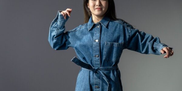 A fashionable woman poses confidently in a denim dress, showcasing modern style.