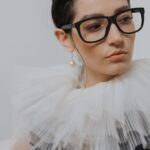 portrait of a stylish woman in a chiffon collar wearing glasses and a pearl earring. 6539156 scaled e1783420145984
