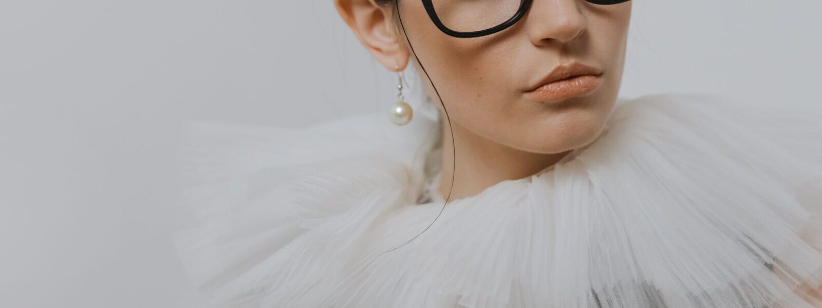 portrait of a stylish woman in a chiffon collar wearing glasses and a pearl earring. 6539156 scaled e1783420145984