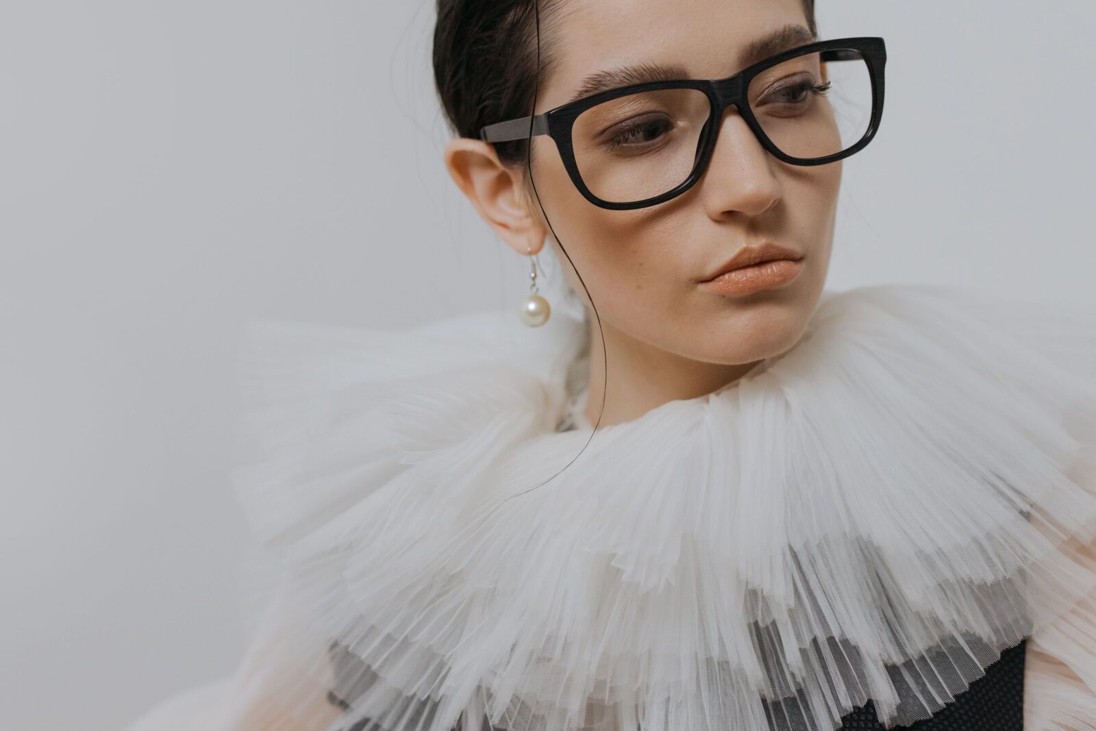 portrait of a stylish woman in a chiffon collar wearing glasses and a pearl earring. 6539156 scaled e1783420145984