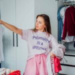 Woman selecting clothes from her wardrobe for donating to a Charity shop. Decluttering Sorting clothes and Cleaning Up. Reuse second hand concept. Conscious consumer sustainable lifestyle