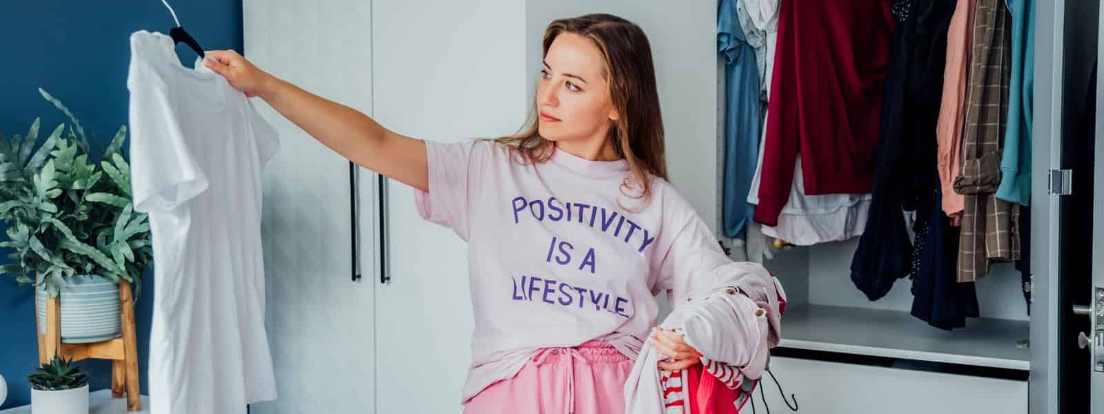 Woman selecting clothes from her wardrobe for donating to a Charity shop. Decluttering Sorting clothes and Cleaning Up. Reuse second hand concept. Conscious consumer sustainable lifestyle