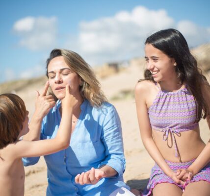 A mother with her kids applying sunscreen on a sunny beach in Portugal.