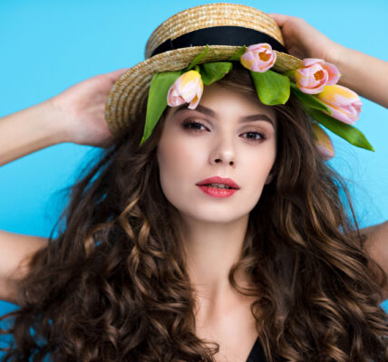 Attractive young woman in canotier hat with pink tulip
