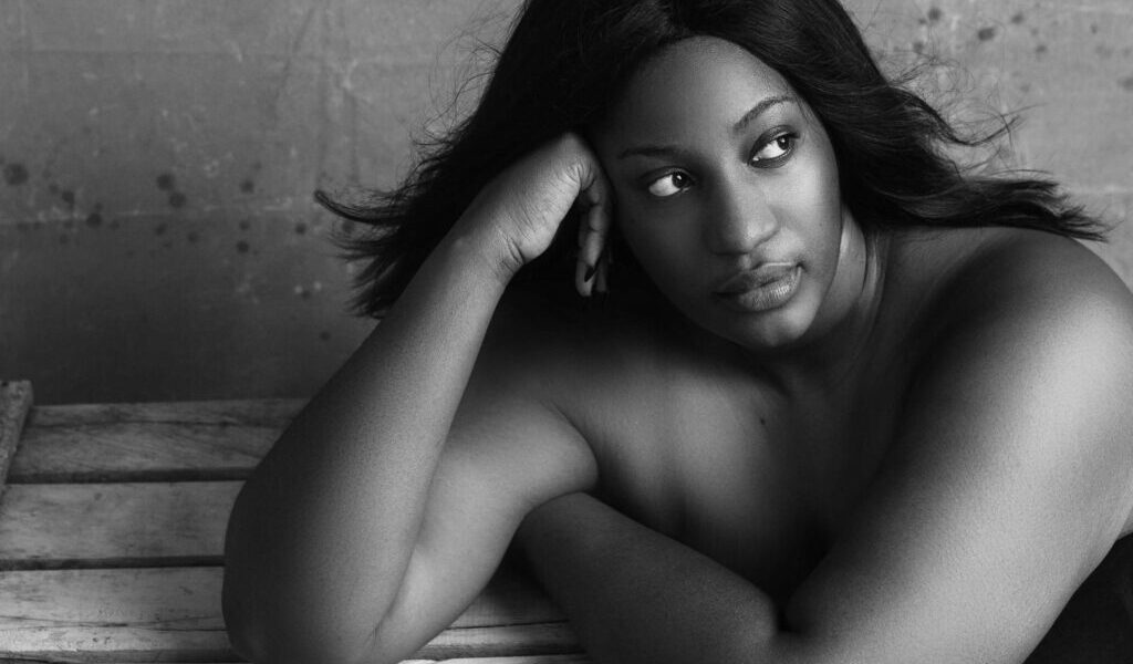 Black and white high angle of plump African American female with flowing hair thinking on problem and looking away