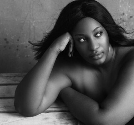 Black and white high angle of plump African American female with flowing hair thinking on problem and looking away